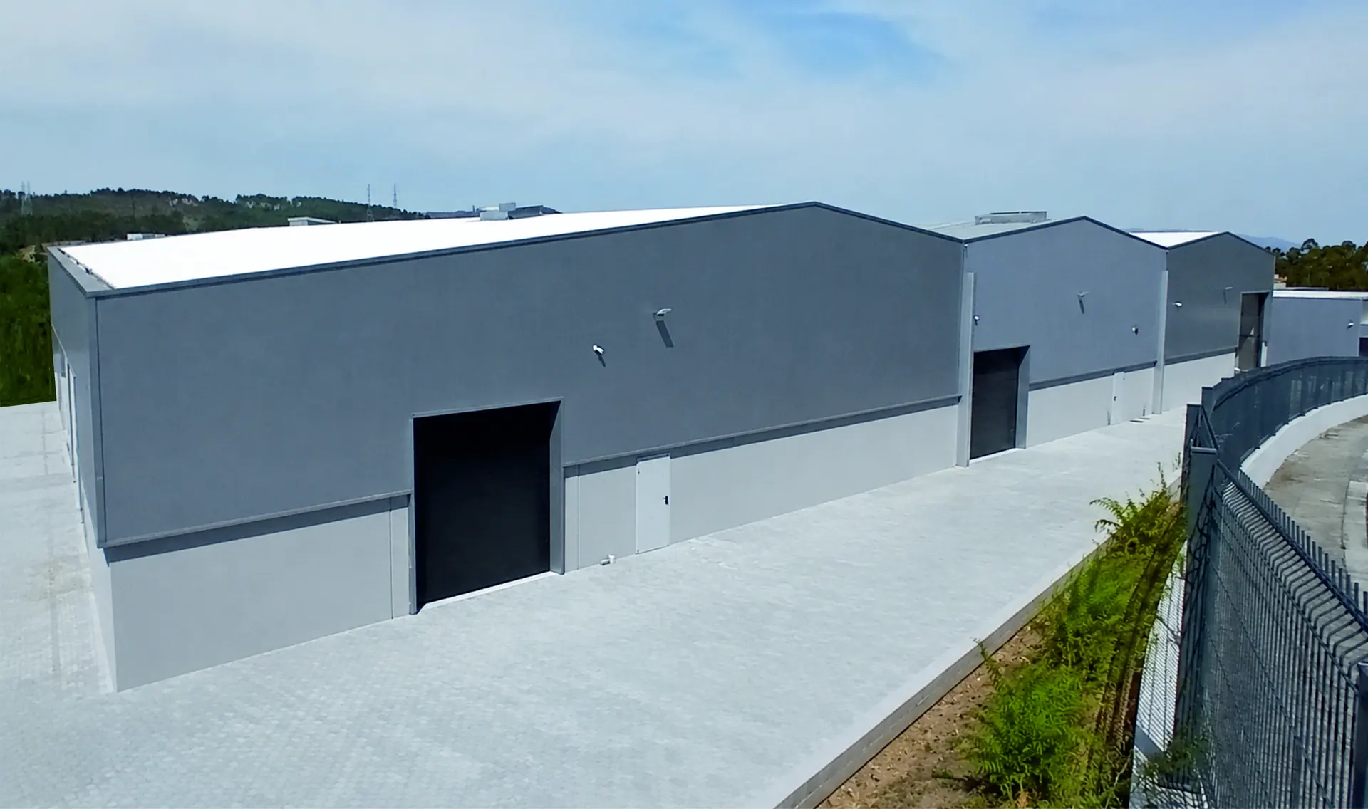 Vista exterior do pavilhão industrial na Zona Industrial da Queijada, Ponte de Lima, com portão de carga aberto